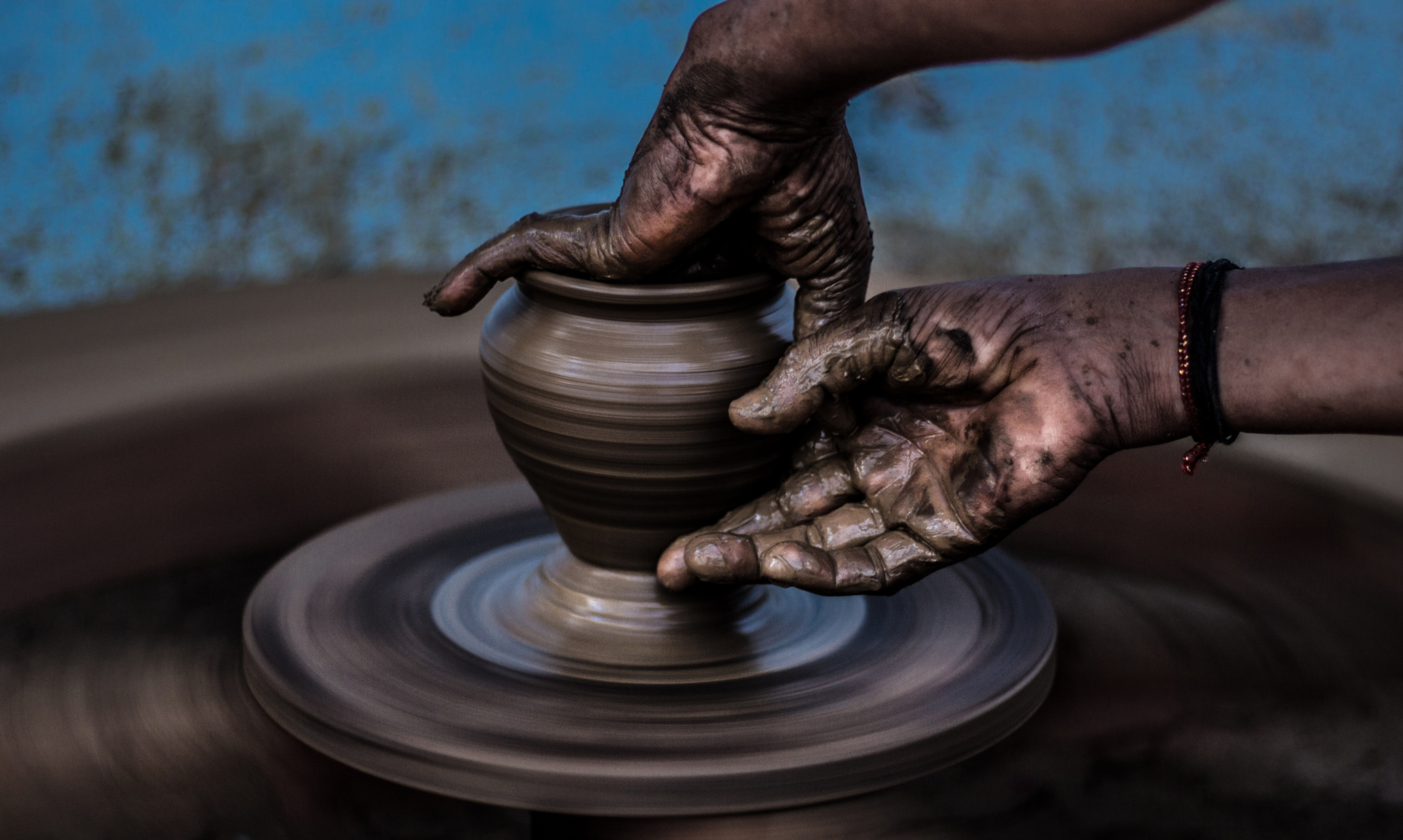 Hands shaping clay on a pottery wheel
